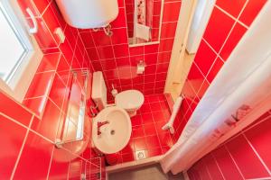 a red bathroom with a toilet and a mirror at Apartment Dumičić 2 in Rab