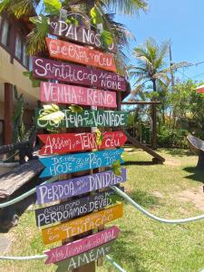 a stack of signs on a pole in the grass at Pousada Potigua in Maricá