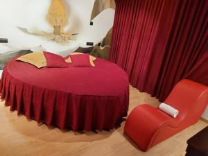 a bedroom with a red bed and a red chair at Motel Acropolis in Camponaraya