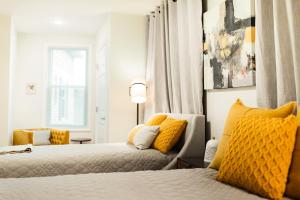 a bedroom with two beds with yellow pillows at The Inn at Newton Highlands in Newton