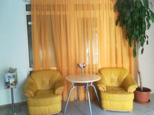 two yellow chairs and a table and a table and chairs at Borisz Apartman Zalakaros in Zalakaros