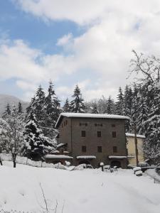 un edificio cubierto de nieve con árboles en el fondo en GARFAGNANA spazioso appartamento, relax! prenotaz min 3 giorni, en Piazza al Serchio