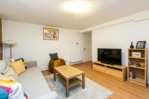 uma sala de estar com um sofá e uma televisão de ecrã plano em NEW Stylish 1 Bedroom Flat with Garden London em Londres