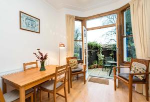 uma sala de jantar com uma mesa de madeira e cadeiras em NEW Stylish 1 Bedroom Flat with Garden London em Londres