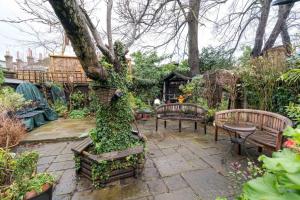 a garden with benches and a table and a tree at NEW Stylish 1 Bedroom Flat with Garden London in London