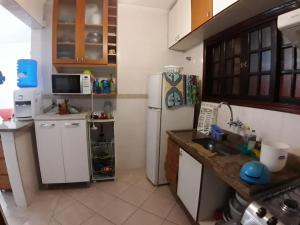 a kitchen with a white refrigerator and a sink at Meu Cantinho in Itanhaém