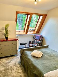 a bedroom with a bed and a chair and windows at APARTAMENT GIMNAZJALNA 8a (Maria Mąka) in Zakopane