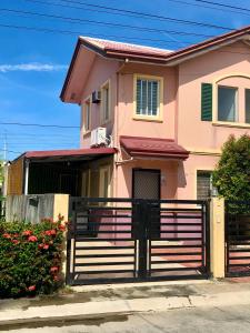 uma casa cor-de-rosa com uma vedação à frente. em Downtown Prominenza 844 em Baliuag