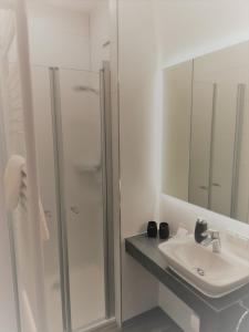 a white bathroom with a shower and a sink at Hotel & Restaurant Alte Molkerei Kölleda in Kölleda