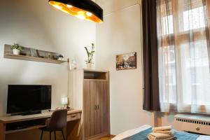een slaapkamer met een televisie en een bureau met een stoel bij Pásti Centrál apartment. in Debrecen