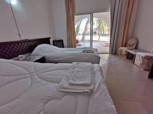 two beds in a room with a large window at Azraq Rest House in Al Azraq ash Shamālī