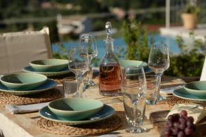 a table with plates and glasses and a bottle of wine at Villa Melanthi Kassiopi Corfu in Kassiopi