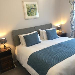 a bedroom with a large bed with blue and white pillows at Spurwing Guest House in Wareham +11 photos