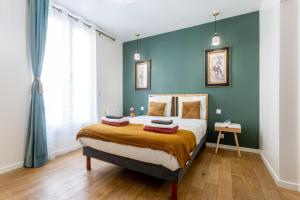 a bedroom with a large bed with blue walls at StayLib - APPARTEMENT 2 PIECES AUX PORTES DE PARIS in Saint-Ouen