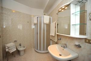 a bathroom with a sink and a toilet and a mirror at Hotel Derby in Bormio +62 photos