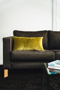 a black couch with a yellow pillow and a table at Daylesford Spa Accommodation in Daylesford