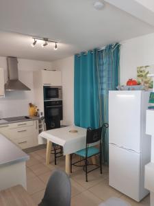 a kitchen with a white table and a white refrigerator at Appartement face à la marina du marin martinique in Le Marin