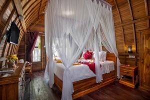 a bedroom with a canopy bed in a wooden cabin at Santen Beach Bungalows in Nusa Penida