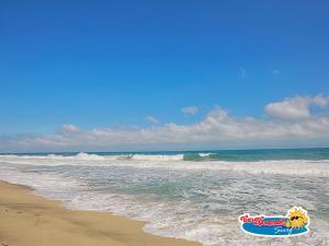 ein Schild am Strand neben dem Meer in der Unterkunft Casa Grande Surf in Guachaca