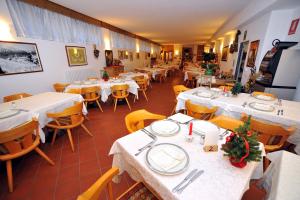 a dining room with white tables and yellow chairs at Hotel Derby in Bormio