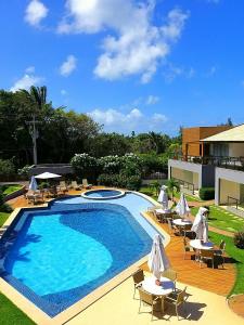 una gran piscina con mesas y sombrillas blancas en Solaris Village Imbassaí, en Salvador