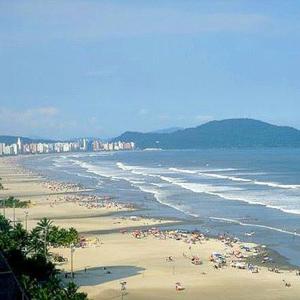a beach with a lot of people and the ocean at Apartamento aconchegante 1 quadra da praia in Praia Grande