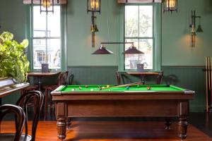 a pool table in a room with green walls and windows at The Royal Hotel Featherston - Boutique Hotel in Featherston