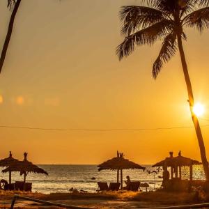 a beach with umbrellas and the ocean at sunset at AZ Family Resort in Ngapali