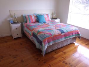 sypialnia z łóżkiem z kolorową kołdrą w obiekcie Glenelg Sea-Breeze w mieście Adelaide