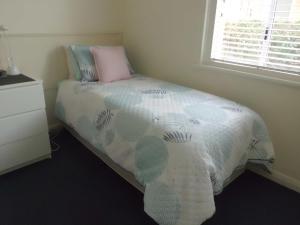 1 dormitorio con cama con almohada y ventana en Glenelg Sea-Breeze en Adelaida