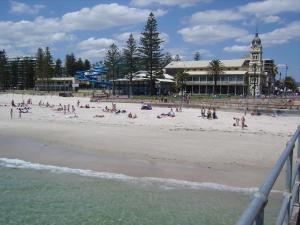 een groep mensen op een strand met een gebouw bij Glenelg Sea-Breeze in Adelaide