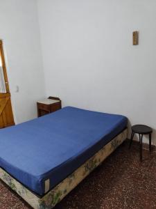 Cama en habitación con mesa y taburete en PH Los Nietos en Quequén