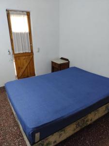 Un dormitorio con una cama azul y una puerta en PH Los Nietos en Quequén