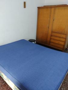 1 dormitorio con 1 cama azul y armario de madera en PH Los Nietos en Quequén