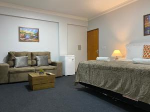 a hotel room with a bed and a couch at Quarto Luxo Silver in Anápolis