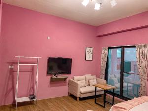 a living room with pink walls and a tv at Mo Dou Homestay in Taitung City