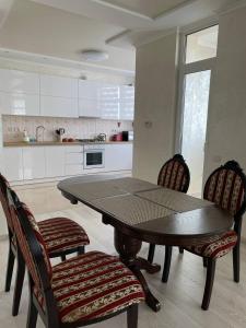 eine Küche mit einem Tisch und 2 Stühlen sowie eine Küche mit weißen Schränken in der Unterkunft апартаменти люкс роксолани 16 in Truskawez