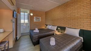 a hotel room with two beds and a television at Goondiwindi Motel in Goondiwindi