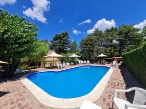 a swimming pool with chairs and umbrellas at Posada Aitue in Villa General Belgrano