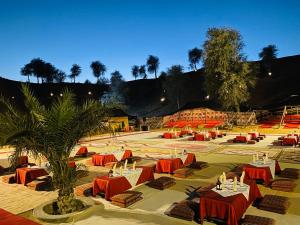 un patio con mesas y sillas rojas y una palmera en Bedouin Oasis Desert Camp- Ras Al Khaimah, en Ras al Khaimah