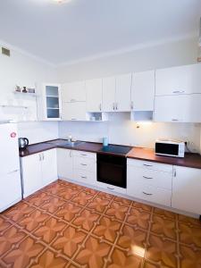 a kitchen with white cabinets and a brown floor at Rent Kiev Apartment 2 min metro Chernihivska in Kyiv
