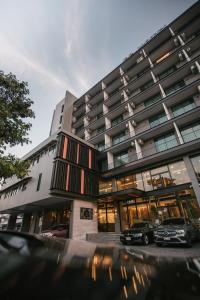 a building with two cars parked in front of it at 56 Hotel in Bangna