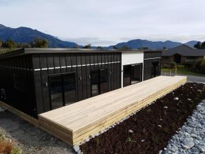 a black and white house with a wooden deck at Stony Creek, 3 bedroom home, Franz Josef in Franz Josef