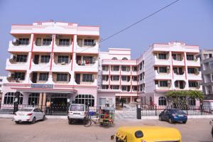 un gran edificio blanco con coches estacionados frente a él en Hotel SagarPriya, en Digha