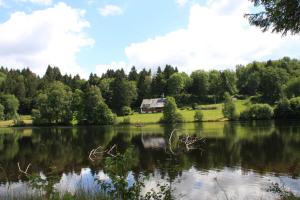 a view of a lake with a house in the background at Klosterweiherhof in Dachsberg im Schwarzwald