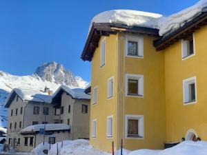 馬洛亞的住宿－Ca del Forno St Moritz，一座黄色的建筑,上面有雪