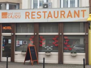 a restaurant with a sign in front of a building at Hotel Cajou in De Panne