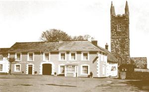 a black and white photo of a building with a church at The Bradworthy Inn in Holsworthy