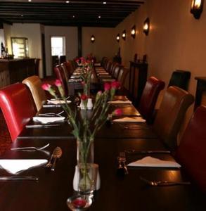 una mesa larga en un restaurante con rosas en un jarrón en The Bradworthy Inn, en Holsworthy