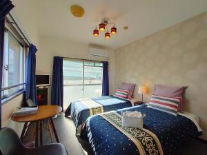a bedroom with two beds and a table and a window at Coco Fukuoka Chiyo in Fukuoka